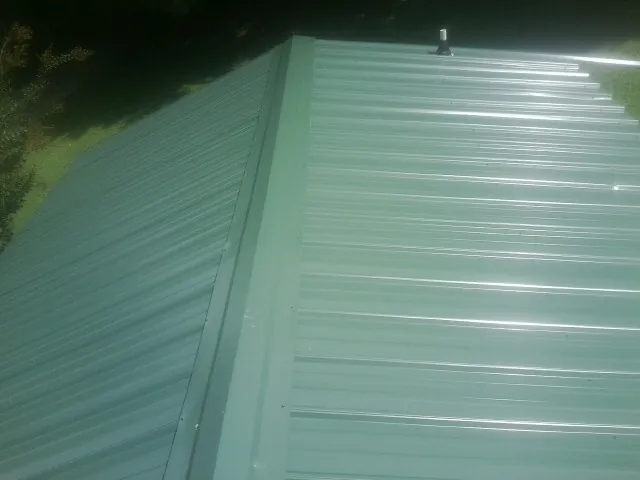 New green metal panels meeting at the ridge of a roof — Flat Roof Repair work by our crew in Richlands