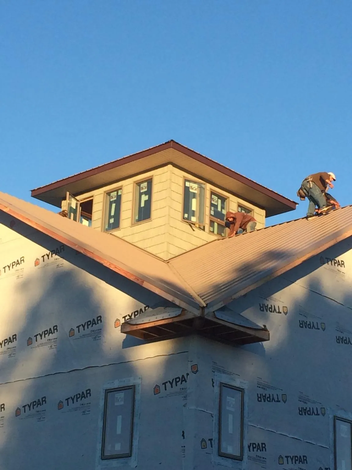 Roofers working around a rooftop cupola on a new metal roof at sunset — Roof Waterproofing in Richlands by Roofing Brothers